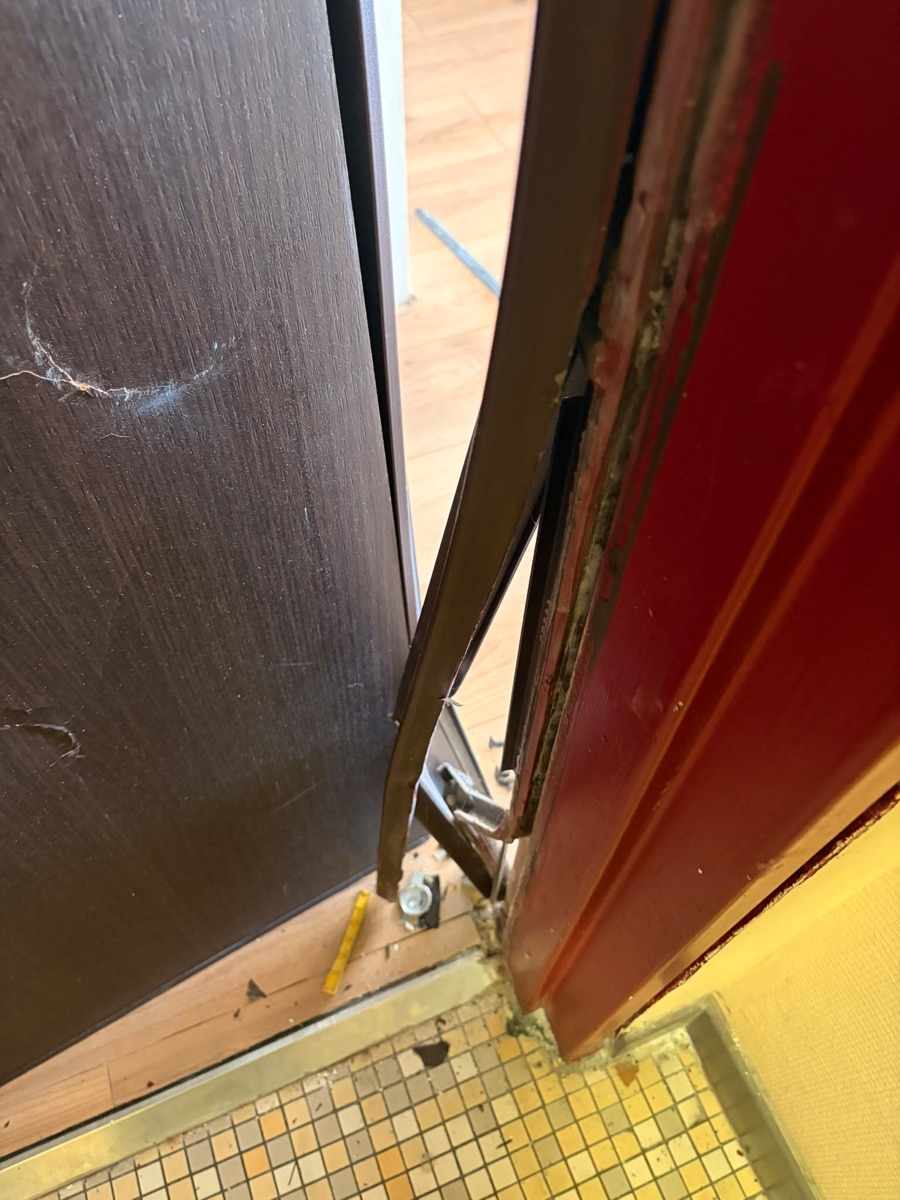 Chant de porte détruit avec gâche arrachée et débris au sol après effraction